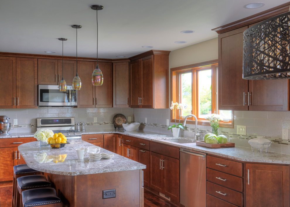 Enclosed kitchen - large transitional l-shaped dark wood floor enclosed kitchen idea in Milwaukee with a drop-in sink, shaker cabinets, medium tone wood cabinets, granite countertops, white backsplash, porcelain backsplash, stainless steel appliances and an island