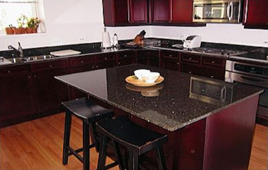 Inspiration for a mid-sized l-shaped light wood floor kitchen remodel in Chicago with an undermount sink, shaker cabinets, dark wood cabinets, granite countertops, ceramic backsplash, stainless steel appliances and an island