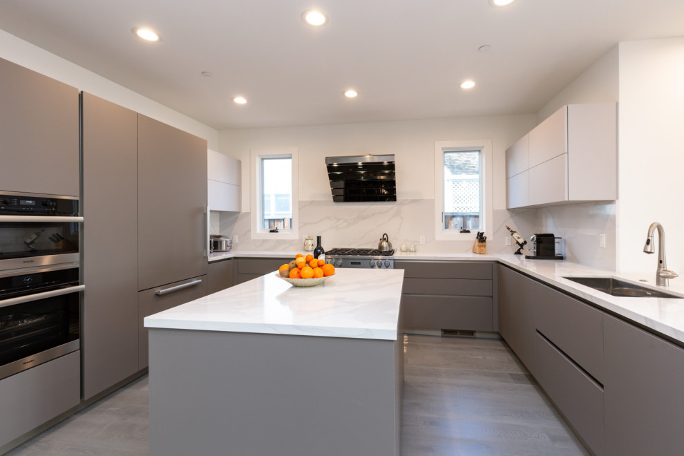 Design ideas for a large modern u-shaped open plan kitchen in San Francisco with an undermount sink, flat-panel cabinets, brown cabinets, glass benchtops, grey splashback, stainless steel appliances, with island, grey floor and grey benchtop.