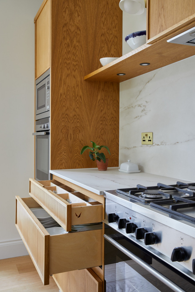 Inspiration for a mid-sized contemporary l-shaped eat-in kitchen in London with recessed-panel cabinets, medium wood cabinets, quartz benchtops, white splashback, stone slab splashback, with island and white benchtop.