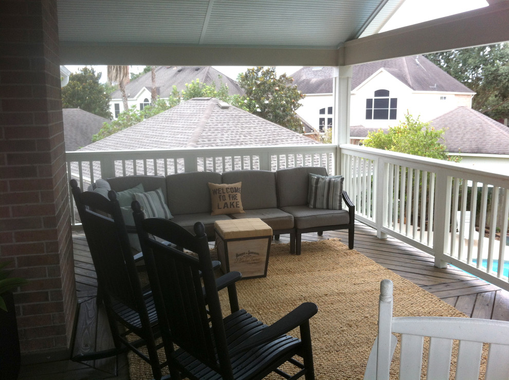 Large traditional backyard deck in Houston with a roof extension.