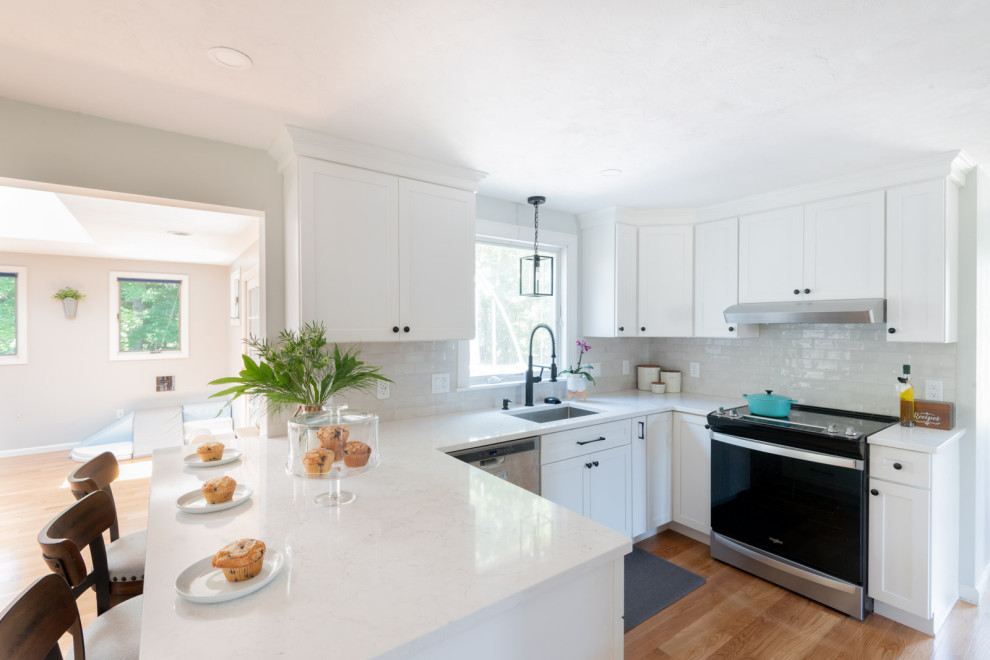 Mid-sized transitional u-shaped medium tone wood floor and brown floor enclosed kitchen photo in Boston with an undermount sink, shaker cabinets, white cabinets, quartz countertops, white backsplash, subway tile backsplash, stainless steel appliances, a peninsula and white countertops