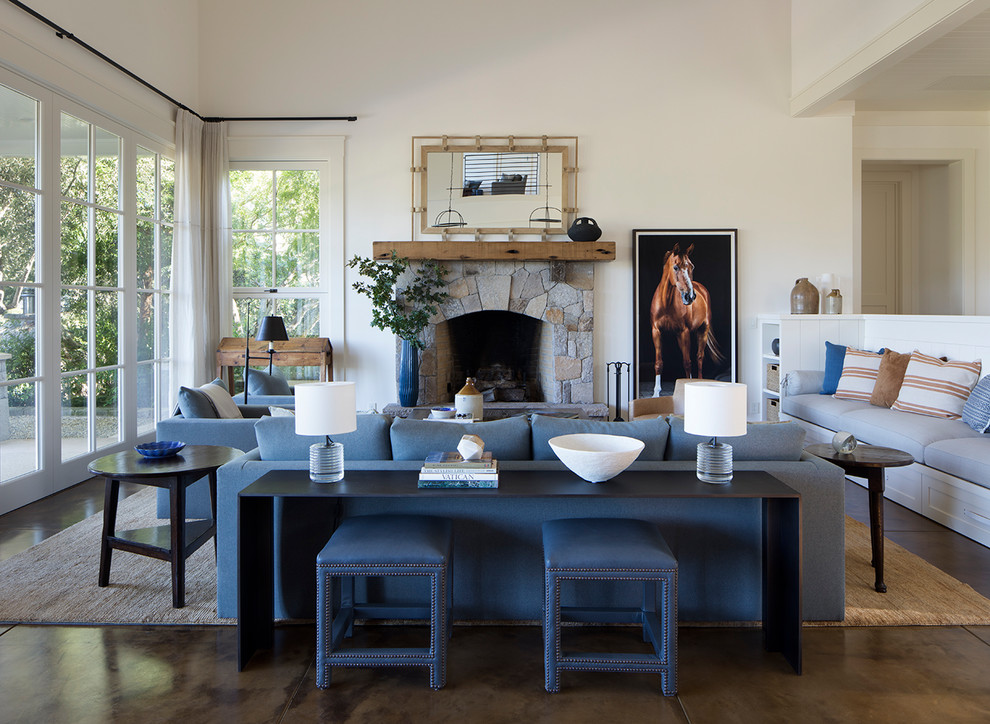 Photo of a country formal open concept living room in San Francisco with white walls, a standard fireplace, a stone fireplace surround, brown floor and concrete floors.
