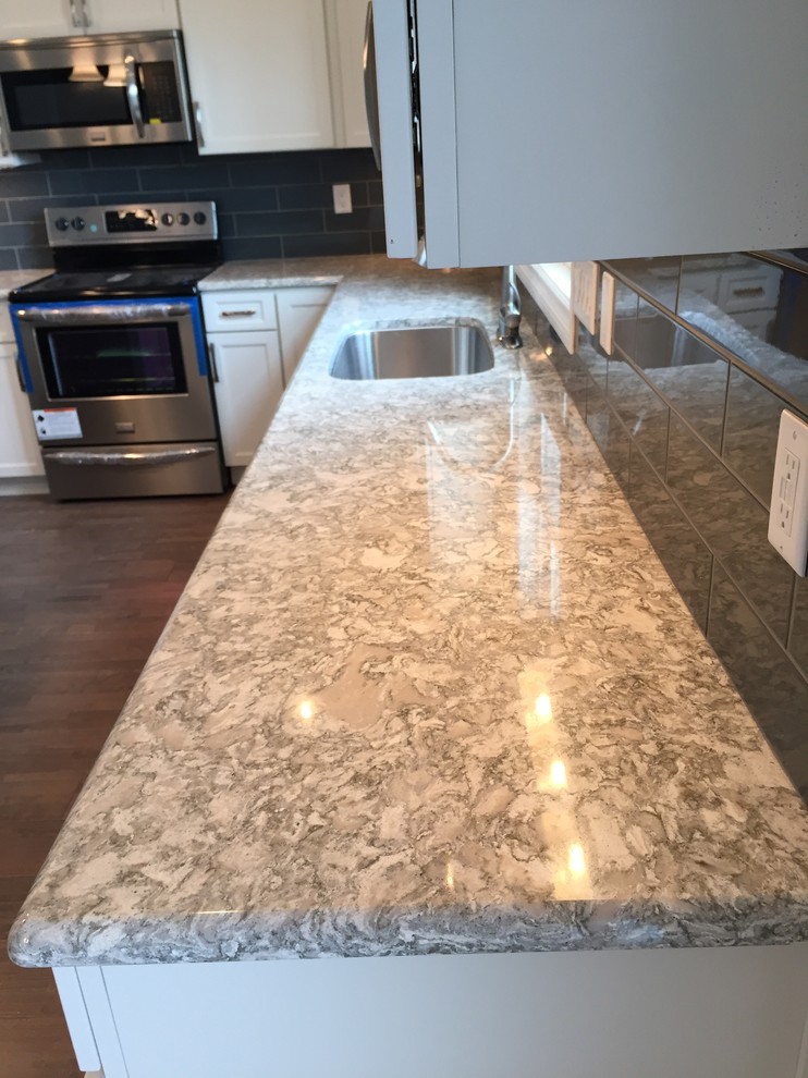 Open concept kitchen - large transitional l-shaped open concept kitchen idea with an undermount sink, raised-panel cabinets, white cabinets, quartz countertops, gray backsplash, stainless steel appliances and an island
