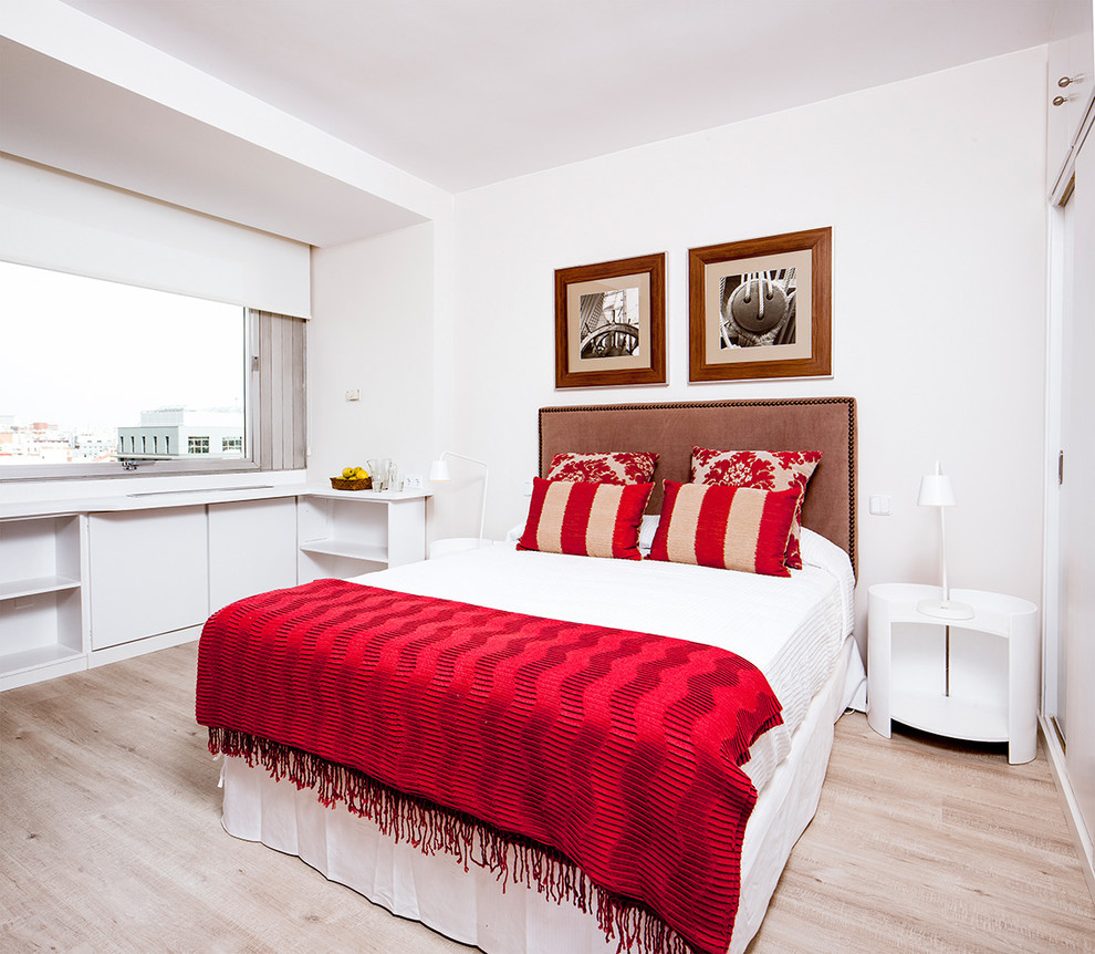 Design ideas for a mid-sized transitional master bedroom in Madrid with white walls, light hardwood floors and no fireplace.
