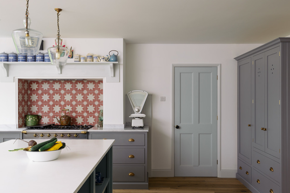 Mid-sized country l-shaped eat-in kitchen in Other with a double-bowl sink, shaker cabinets, grey cabinets, orange splashback, ceramic splashback, stainless steel appliances, medium hardwood floors, with island and brown floor.