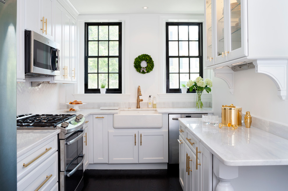 Photo of a transitional galley separate kitchen in DC Metro with quartzite benchtops, white splashback, subway tile splashback, stainless steel appliances, painted wood floors, shaker cabinets, white cabinets, a farmhouse sink and black floor.