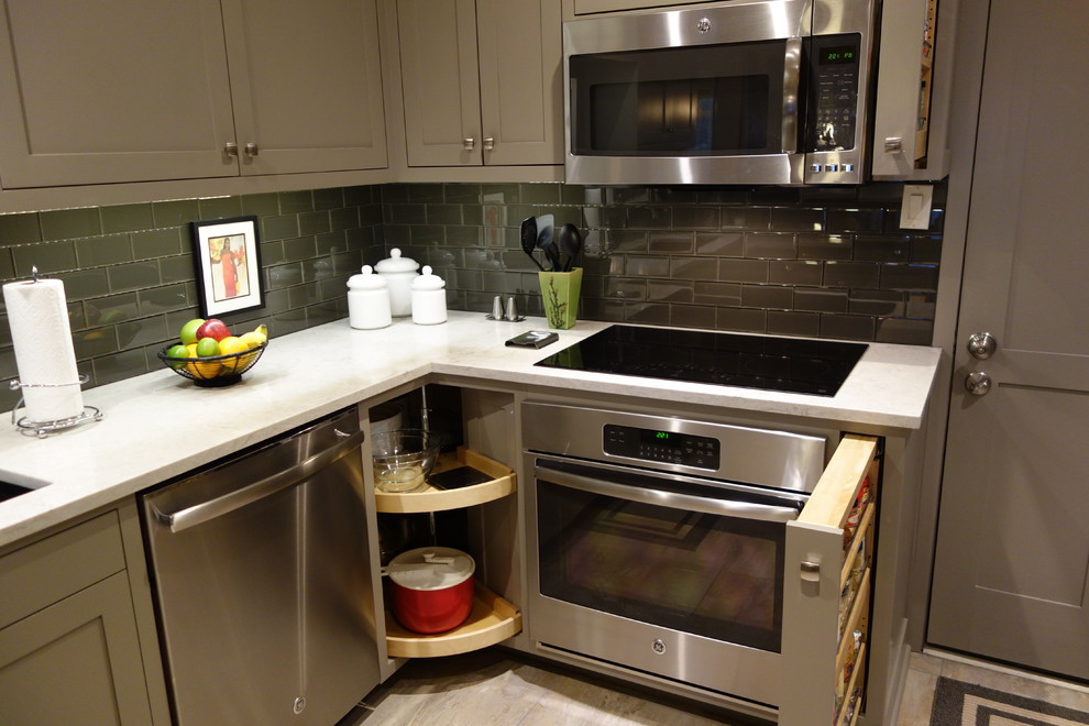 Example of a small transitional u-shaped ceramic tile enclosed kitchen design with an undermount sink, shaker cabinets, gray cabinets, quartz countertops, gray backsplash, glass tile backsplash, stainless steel appliances and a peninsula