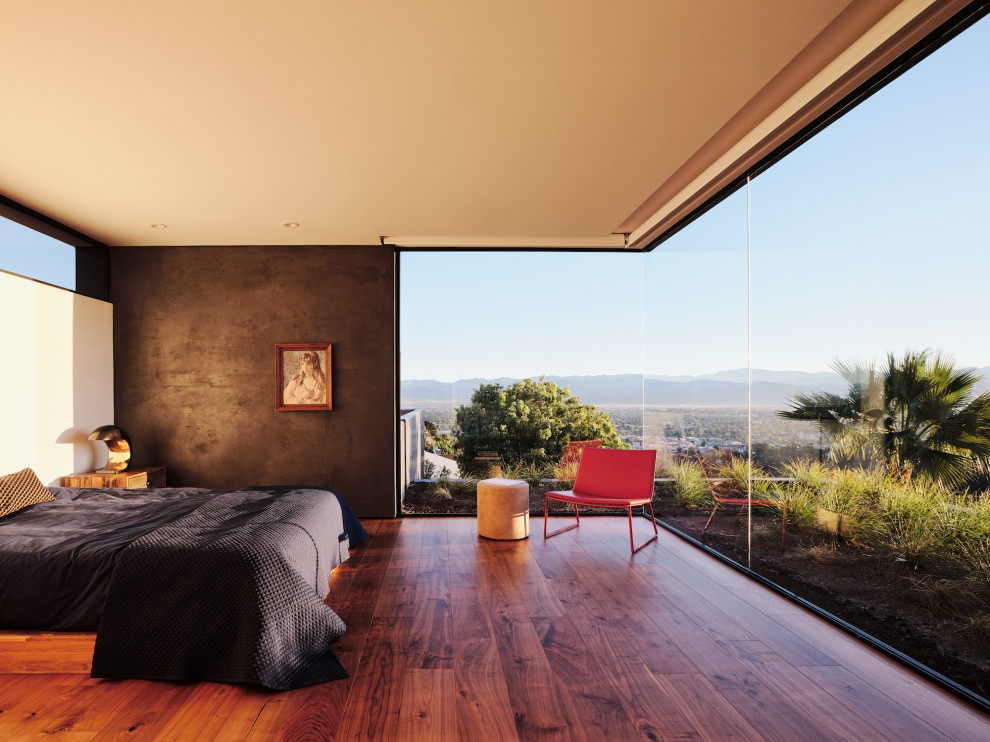 Large modern master bedroom in Los Angeles with grey walls, medium hardwood floors, no fireplace and brown floor.