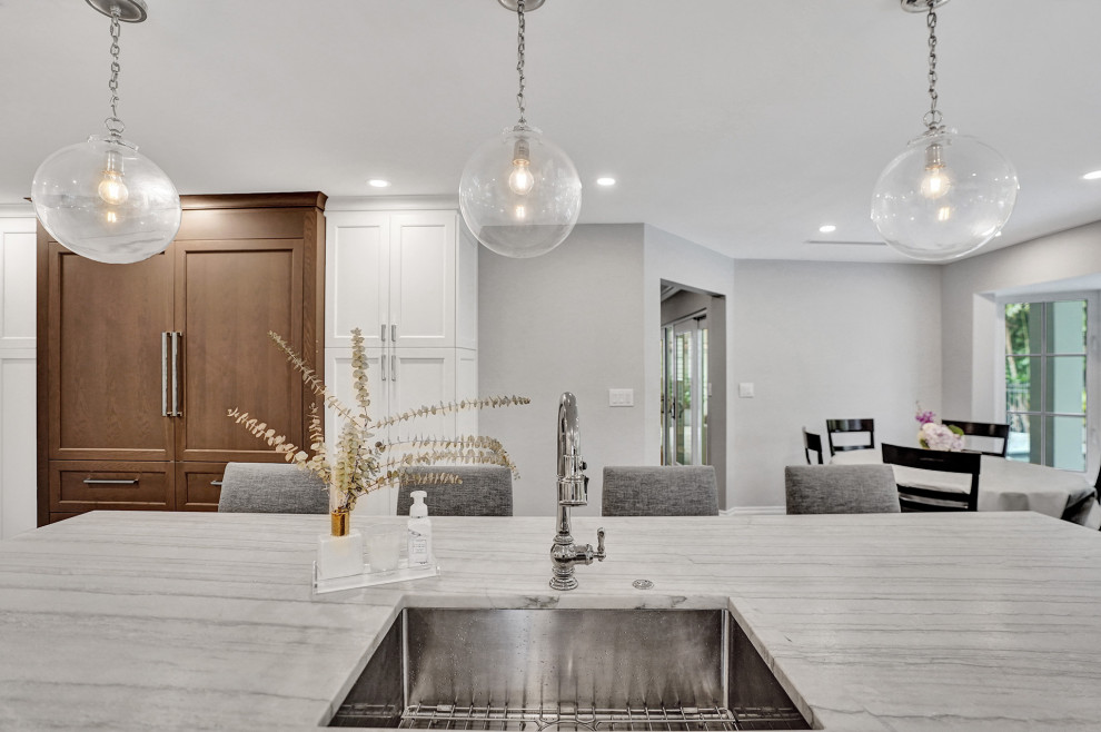 Example of a transitional eat-in kitchen design in Miami with shaker cabinets, white cabinets, white backsplash, an island and white countertops