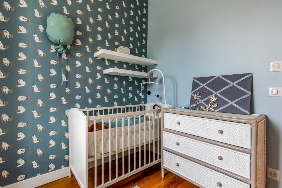 Example of a small trendy light wood floor, brown floor and wallpaper nursery design in Paris with blue walls