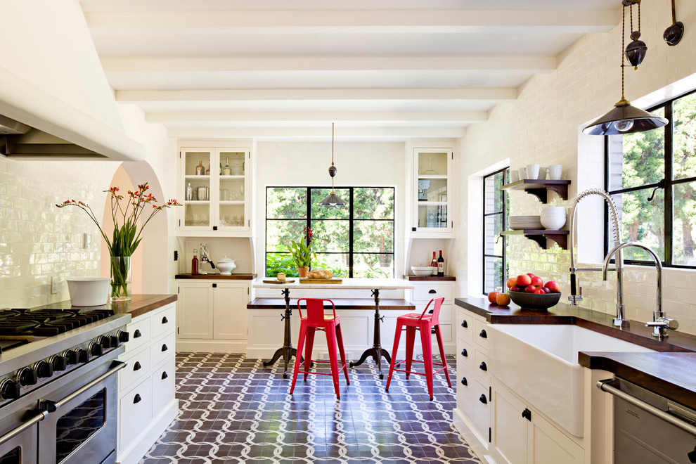Design ideas for a mediterranean galley separate kitchen in Portland with a farmhouse sink, shaker cabinets, white cabinets, wood benchtops, white splashback, subway tile splashback and stainless steel appliances.