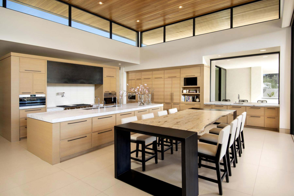 Photo of an expansive contemporary l-shaped open plan kitchen in Phoenix with an undermount sink, flat-panel cabinets, medium wood cabinets, marble benchtops, white splashback, ceramic splashback, stainless steel appliances, with island, beige floor, white benchtop and wood.