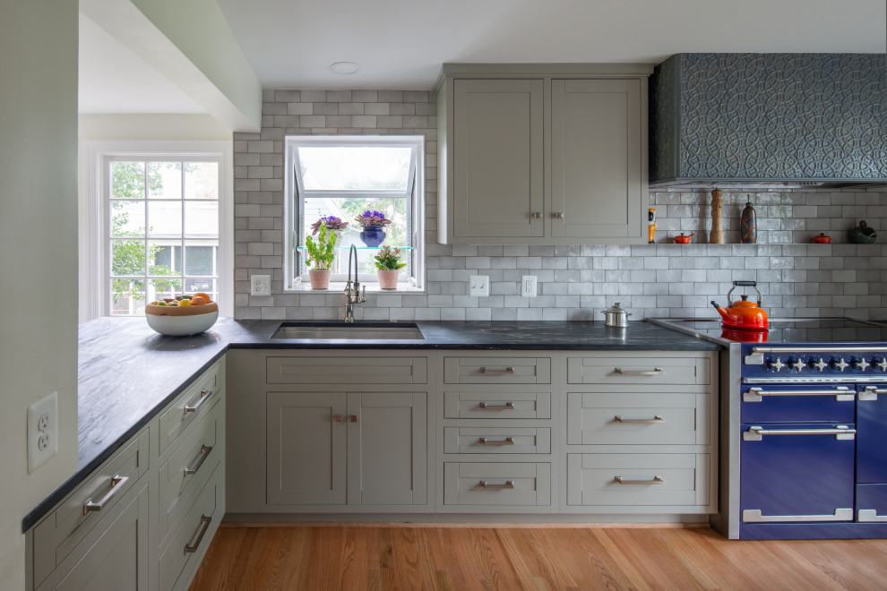 Transitional l-shaped kitchen in DC Metro with an undermount sink, shaker cabinets, grey cabinets, grey splashback, coloured appliances, medium hardwood floors, brown floor and black benchtop.