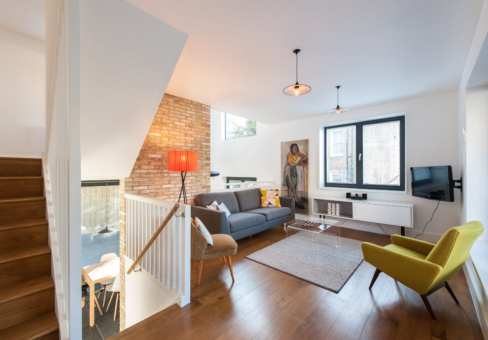 Photo of a contemporary formal living room in London with white walls, medium hardwood flooring and a wall mounted tv.