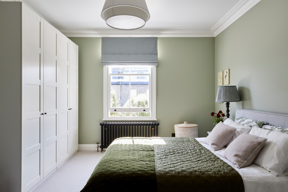 На фото: большая гостевая спальня (комната для гостей) в стиле неоклассика (современная классика) с зелеными стенами, ковровым покрытием и бежевым полом с