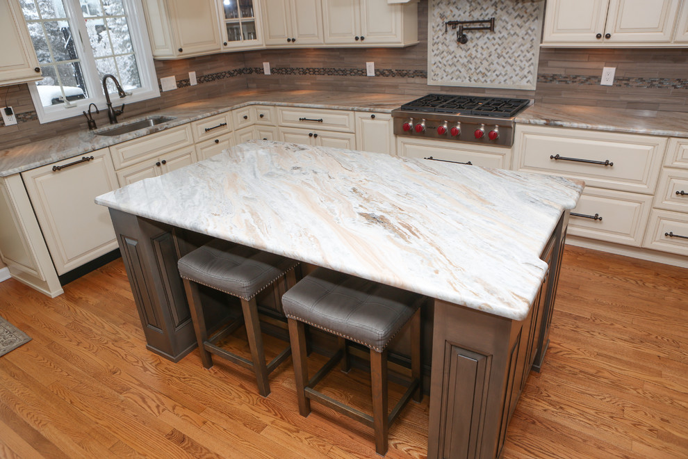 Example of a large transitional u-shaped light wood floor eat-in kitchen design in Newark with an undermount sink, raised-panel cabinets, distressed cabinets, granite countertops, brown backsplash, mosaic tile backsplash, stainless steel appliances and an island