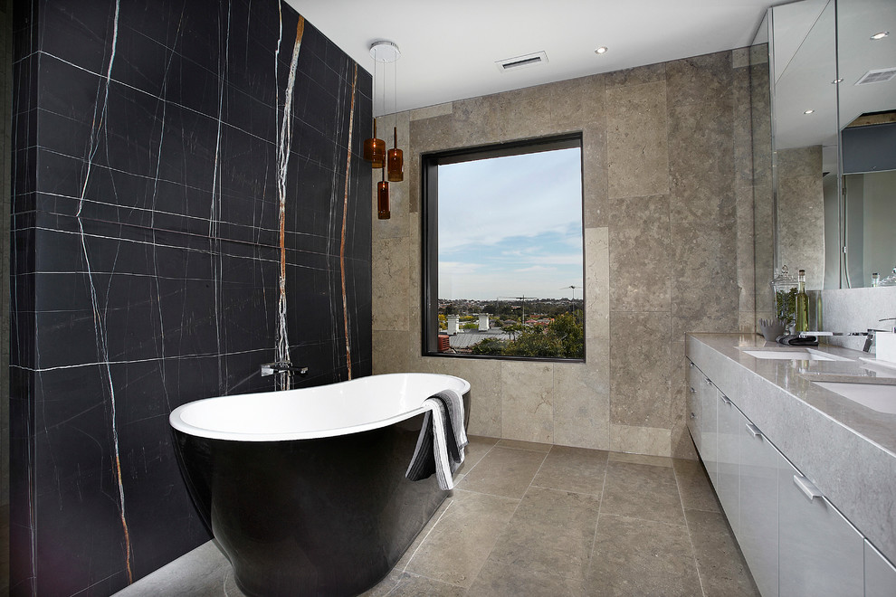 Contemporary bathroom in Melbourne with a freestanding tub, black walls, limestone and grey benchtops.