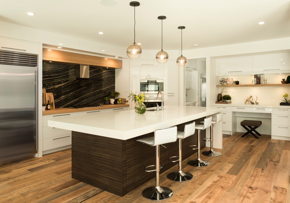 Large trendy single-wall medium tone wood floor and brown floor open concept kitchen photo in Edmonton with flat-panel cabinets, white backsplash, stainless steel appliances, an island, an undermount sink, white cabinets, quartz countertops and marble backsplash