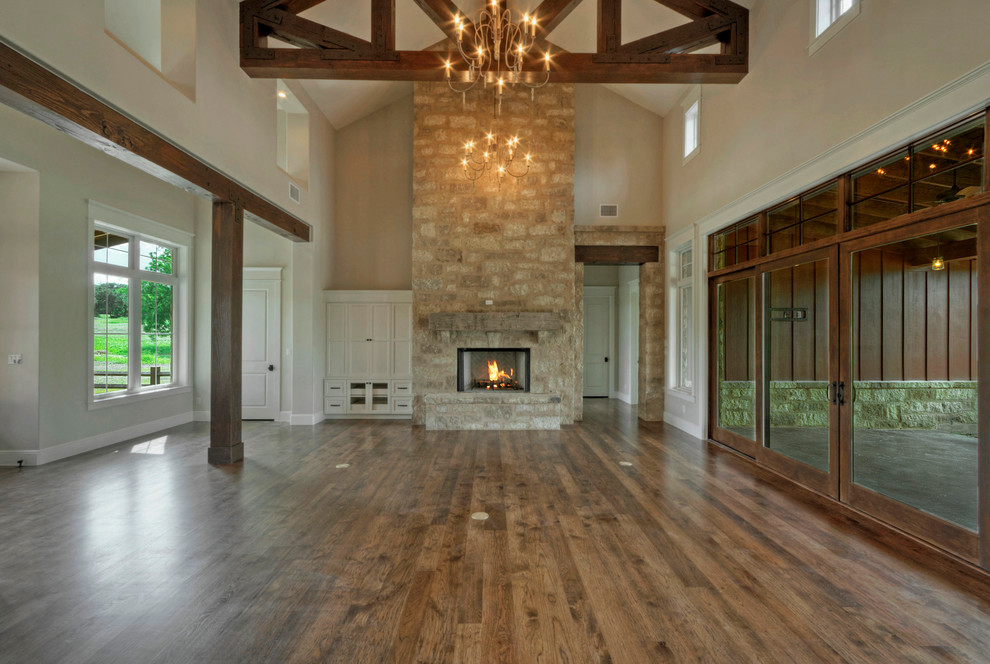 Large country open concept living room in Austin with beige walls, medium hardwood floors, a standard fireplace, a stone fireplace surround and a built-in media wall.