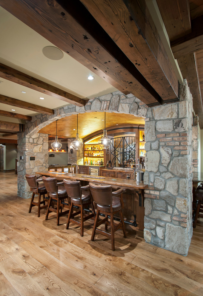Country seated home bar in Vancouver with dark wood cabinets and light hardwood floors.