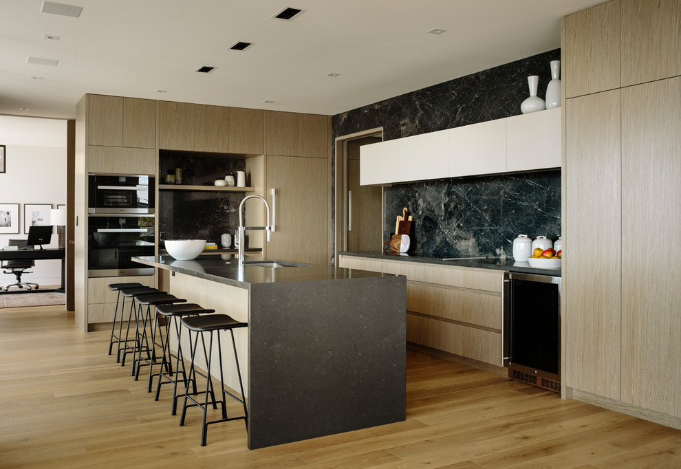 This is an example of a large contemporary l-shaped eat-in kitchen in Vancouver with an undermount sink, flat-panel cabinets, medium wood cabinets, quartz benchtops, porcelain splashback, stainless steel appliances, medium hardwood floors, with island, grey benchtop, black splashback and brown floor.