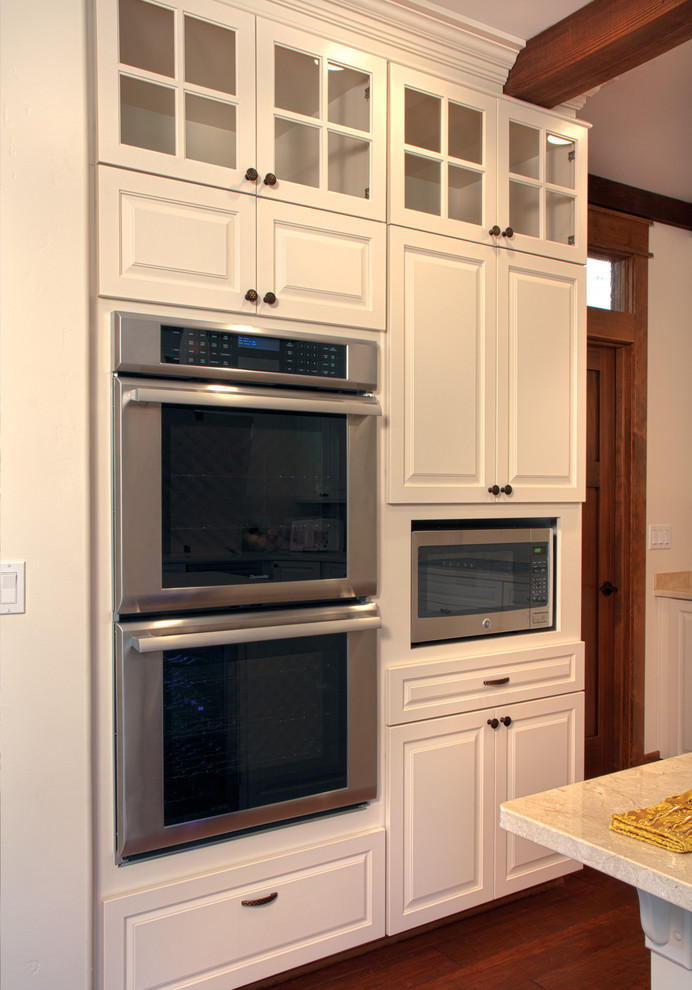 Kitchen - transitional medium tone wood floor kitchen idea with raised-panel cabinets, white cabinets and stainless steel appliances