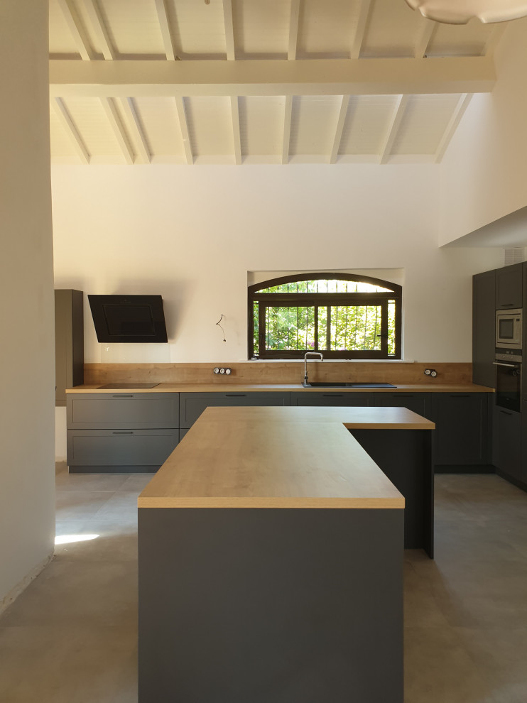 Large modern l-shaped open plan kitchen in Toulouse with with island, an undermount sink, beaded inset cabinets, stainless steel cabinets, wood benchtops, brown splashback, timber splashback, coloured appliances, ceramic floors, grey floor and brown benchtop.
