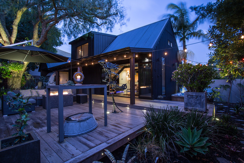 Mid-sized industrial courtyard patio in Auckland with a fire feature, decking and no cover.
