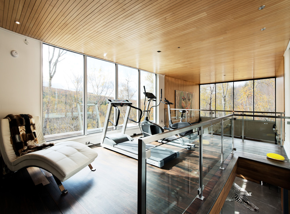 This is an example of a contemporary home gym in Montreal with beige walls, dark hardwood floors and brown floor.