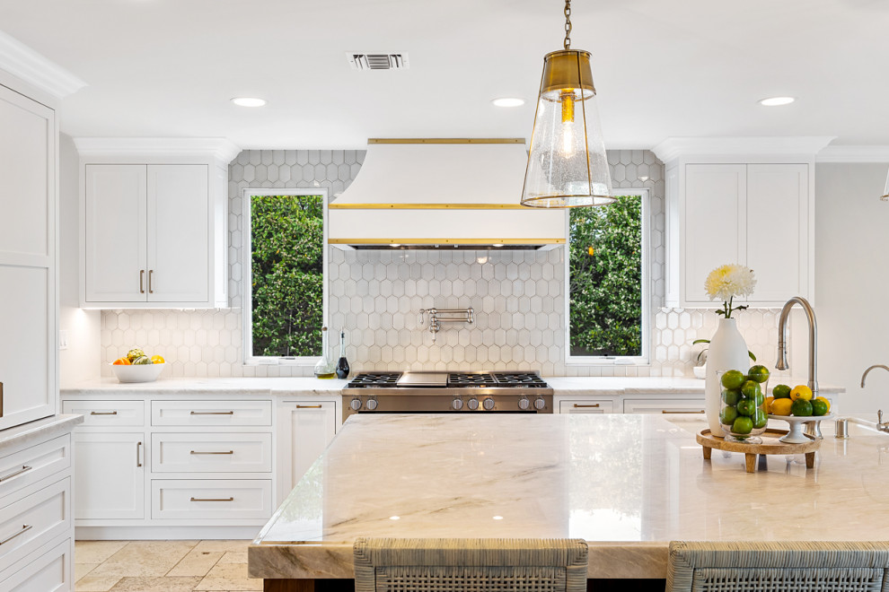 This is an example of a large mediterranean u-shaped open plan kitchen in Los Angeles with a single-bowl sink, recessed-panel cabinets, white cabinets, quartzite benchtops, white splashback, stainless steel appliances, ceramic floors, with island, beige floor and multi-coloured benchtop.