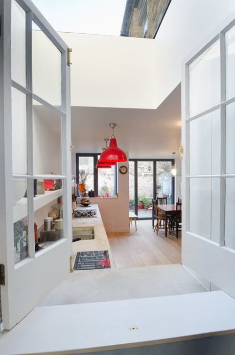Inspiration for a mid-sized contemporary single-wall eat-in kitchen in London with a double-bowl sink, red cabinets, concrete benchtops, metallic splashback and stainless steel appliances.