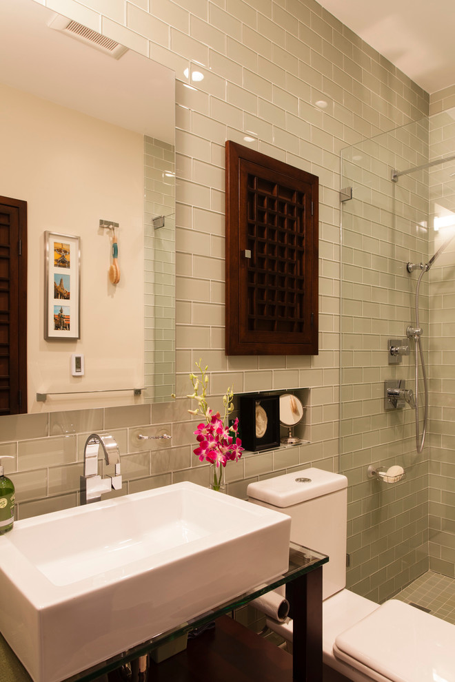Photo of a contemporary bathroom in Boston with a vessel sink, glass benchtops, an alcove shower, a two-piece toilet, beige tile, glass tile and green walls.