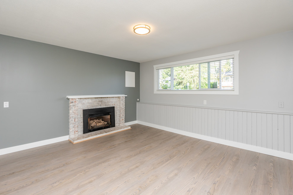 Photo of a large transitional open concept family room in Vancouver with grey walls, light hardwood floors, a standard fireplace, a brick fireplace surround, no tv and beige floor.