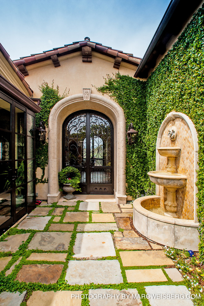 This is an example of a mid-sized mediterranean courtyard partial sun garden in San Diego with a garden path and natural stone pavers.