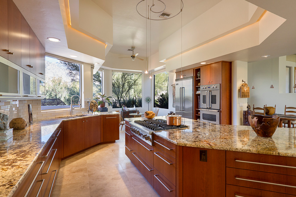 Inspiration for a large contemporary open plan kitchen in Phoenix with an undermount sink, flat-panel cabinets, light wood cabinets, granite benchtops, white splashback, glass tile splashback, stainless steel appliances, travertine floors and with island.