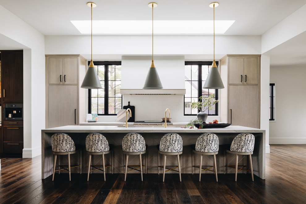 This is an example of a contemporary eat-in kitchen in Chicago with light wood cabinets, white splashback, with island, brown floor and white benchtop.