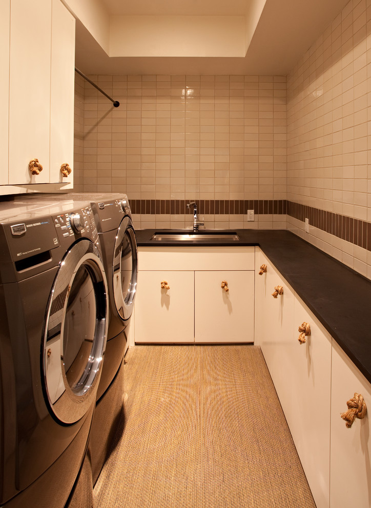 Contemporary laundry room in San Francisco with white cabinets and black benchtop.