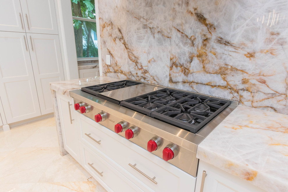 Huge transitional u-shaped marble floor and white floor open concept kitchen photo with an undermount sink, flat-panel cabinets, white cabinets, quartzite countertops, white backsplash, stone slab backsplash and two islands
