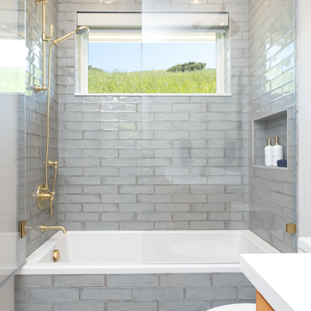 Пример оригинального дизайна: детская ванная комната среднего размера в стиле неоклассика (современная классика) с фасадами в стиле шейкер, оранжевыми фасадами, ванной в нише, душем над ванной, унитазом-моноблоком, серой плиткой, керамической плиткой, серыми стенами, полом из керамогранита, врезной раковиной, столешницей из искусственного кварца, серым полом, душем с распашными дверями, белой столешницей, тумбой под одну раковину и встроенной тумбой
