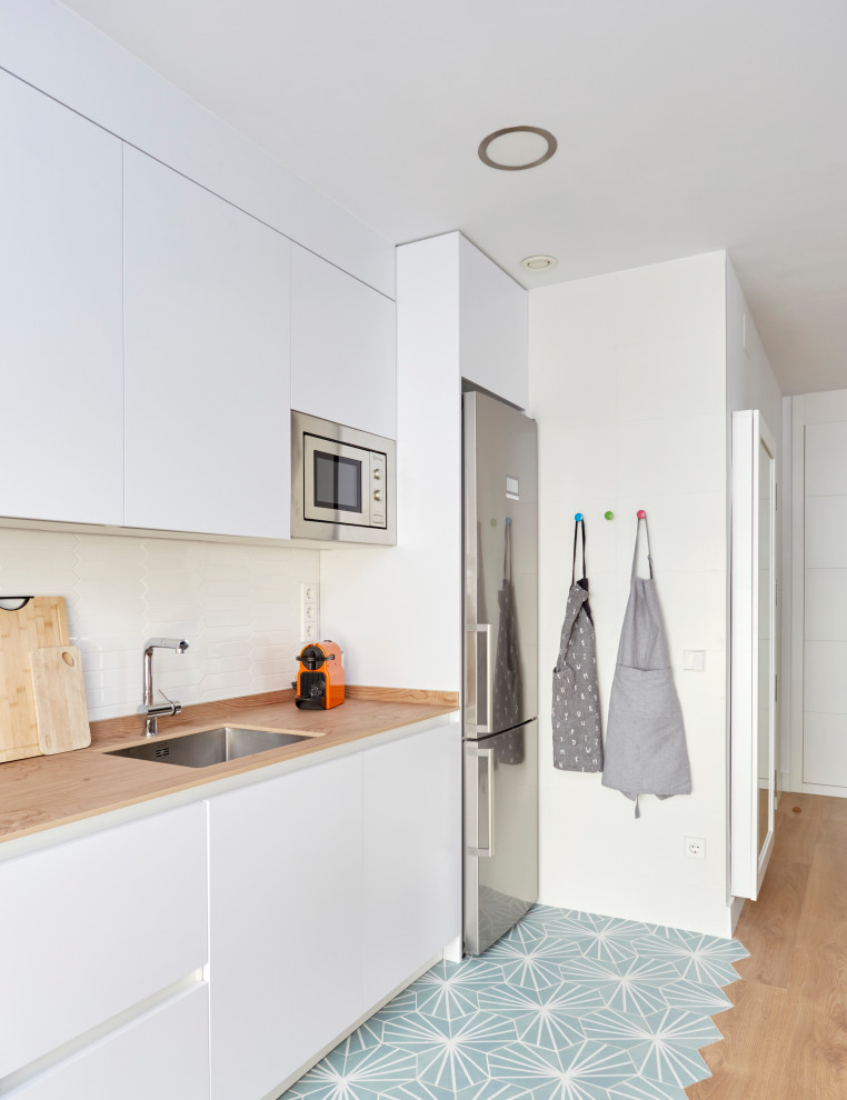 Design ideas for a mid-sized modern kitchen in Madrid with a single-bowl sink, flat-panel cabinets, white cabinets, granite benchtops, white splashback, ceramic splashback, white appliances, ceramic floors, turquoise floor and grey benchtop.
