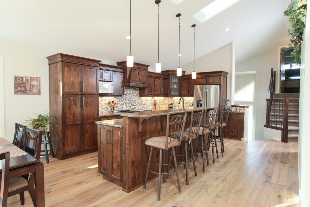 Inspiration for a large transitional l-shaped light wood floor eat-in kitchen remodel in Calgary with shaker cabinets, dark wood cabinets, quartz countertops, gray backsplash, matchstick tile backsplash, stainless steel appliances, an island and an undermount sink