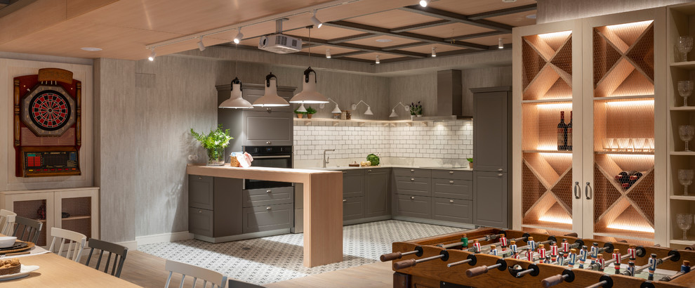 Design ideas for an expansive transitional l-shaped eat-in kitchen in Bilbao with an undermount sink, glass-front cabinets, grey cabinets, quartz benchtops, white splashback, ceramic splashback, stainless steel appliances, ceramic floors, a peninsula, grey floor and white benchtop.