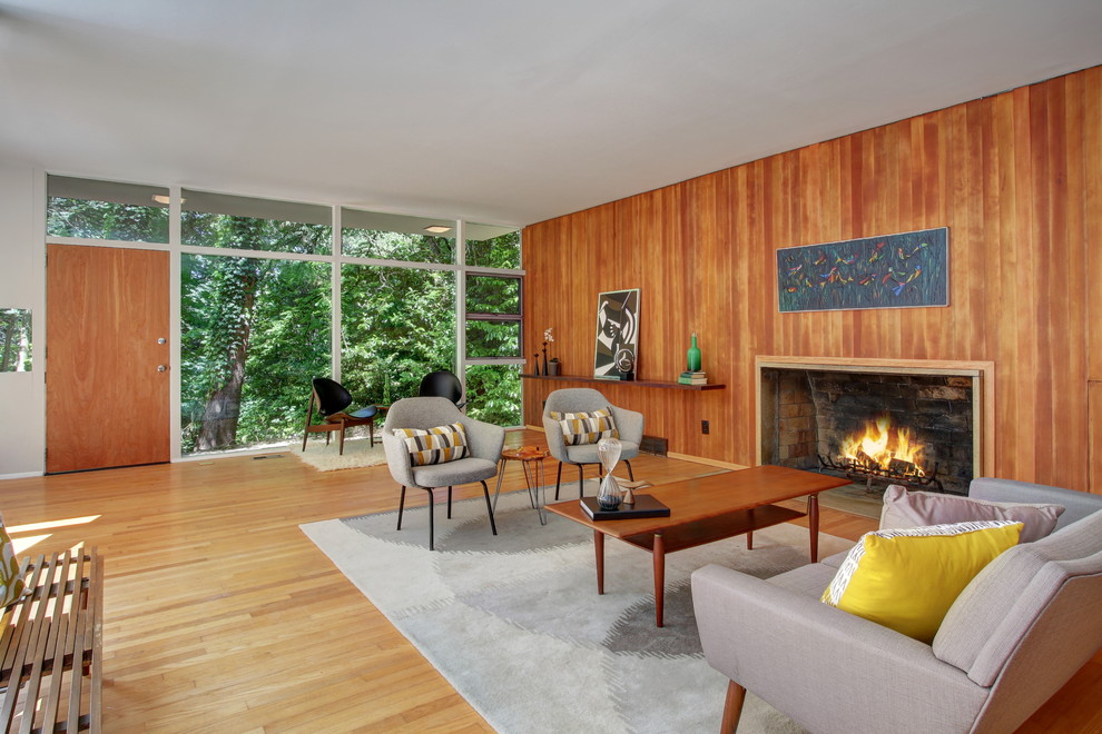 Inspiration for a midcentury living room in Seattle with medium hardwood floors, a standard fireplace and a wood fireplace surround.