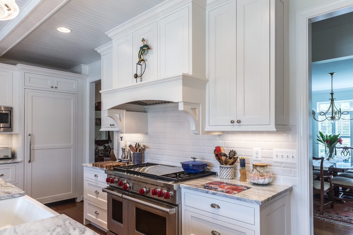 Design ideas for a large transitional open plan kitchen in DC Metro with a farmhouse sink, shaker cabinets, white cabinets, white splashback, subway tile splashback, stainless steel appliances, medium hardwood floors, with island and brown floor.