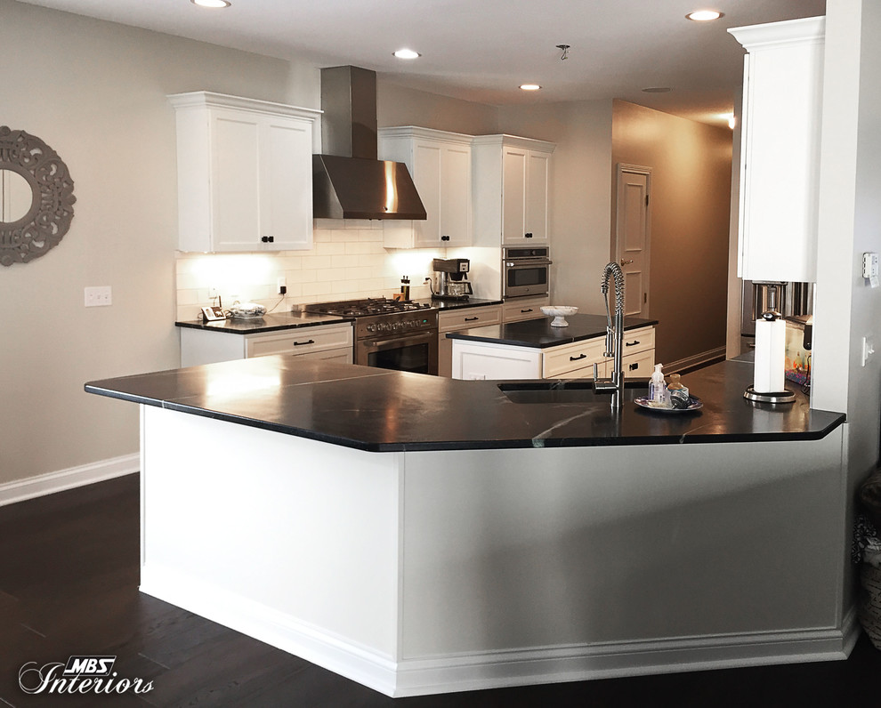 Inspiration for a mid-sized transitional u-shaped dark wood floor and brown floor eat-in kitchen remodel with an undermount sink, recessed-panel cabinets, white cabinets, soapstone countertops, white backsplash, subway tile backsplash, stainless steel appliances and an island