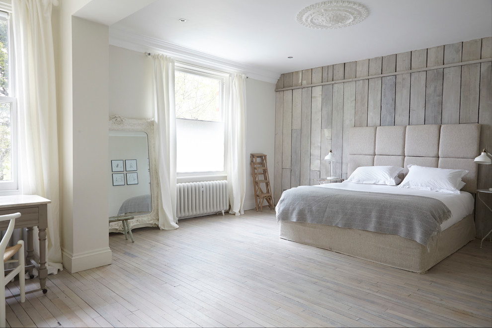 Large contemporary master bedroom in London with beige walls and painted wood floors.