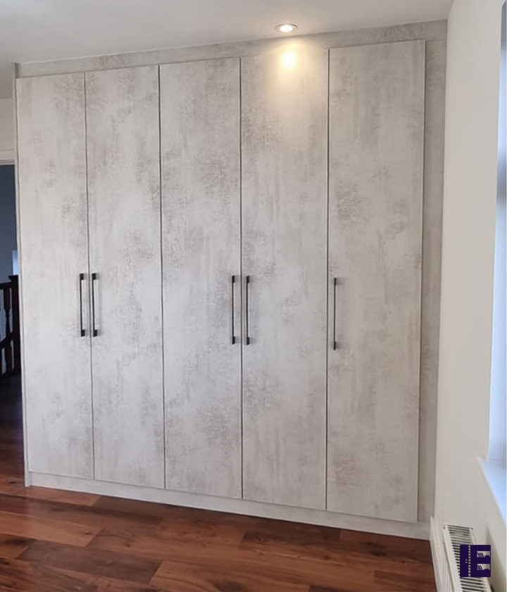 Idées déco pour une petite armoire encastrée moderne avec un placard à porte plane, des portes de placard grises, un sol en contreplaqué et un plafond en bois.