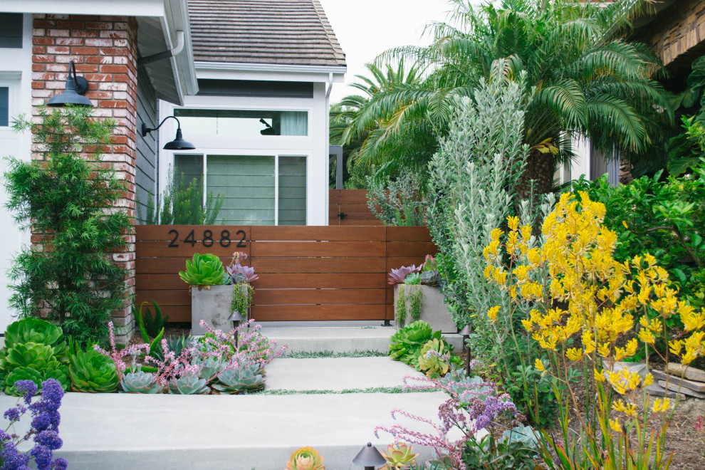 This is an example of a mid-sized contemporary front yard partial sun xeriscape in Orange County with concrete pavers, a garden path and a wood fence.