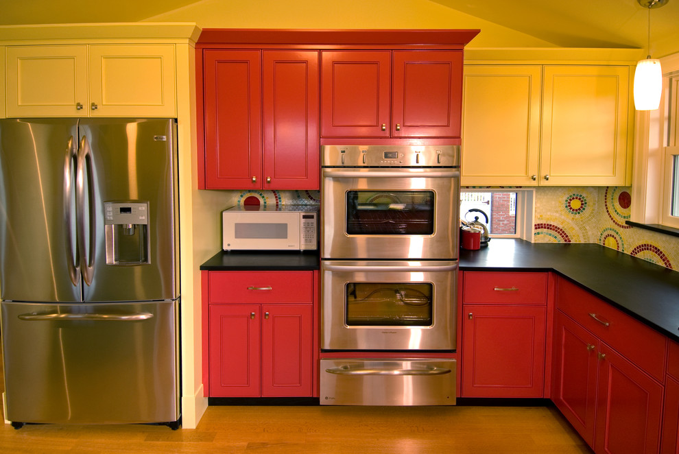 This is an example of a contemporary kitchen in Seattle with recessed-panel cabinets, red cabinets, multi-coloured splashback, mosaic tile splashback and stainless steel appliances.